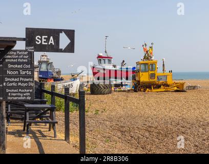 Aldeburgh, Suffolk, Regno Unito. Un cartello su una capanna di pesca che vende pesce affumicato, con un peschereccio sullo sfondo. Foto Stock