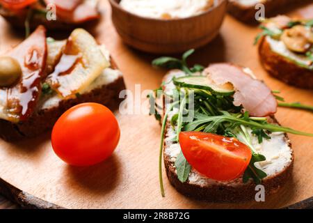 Tavola di legno di gustosi panini con formaggio cremoso e prosciutto, primo piano Foto Stock