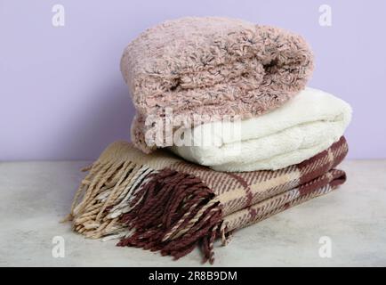 Nuove morbide coperte piegate sul tavolo nuovo muro viola Foto Stock