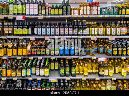 Italia - 31 maggio 2023: Olio d'oliva in bottiglie di vetro di varie marche e tipologie su scaffali per la vendita in un supermercato italiano Foto Stock