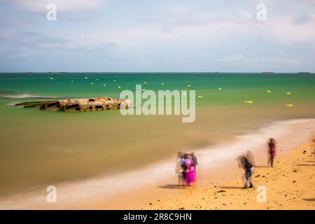 Turisti che scattano foto di fronte ai resti di un porto di Mulberry WW2, Arromanches-les-Bains, Normandia, Francia Foto Stock