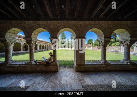 Una donna che legge nel chiostro dell'Abbazia di Saint-Michel de Cuxa, Francia Foto Stock