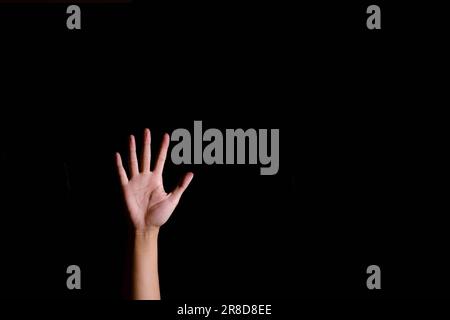 Una mano di un uomo con cinque dita su uno sfondo nero isolato Foto Stock