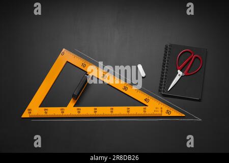 Composizione piatta con triangolo e gesso, su lavagna Foto Stock