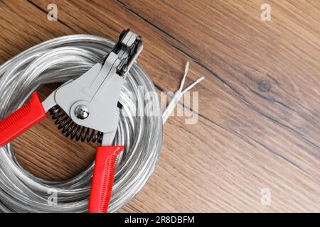 Taglierine e cavo con filo spelato su tavolo in legno, vista dall'alto. Spazio per il testo Foto Stock