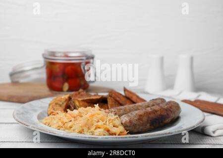 Piatto con crauti, salsicce e patate su tavola di legno bianco Foto Stock
