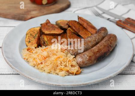 Piatto con crauti, salsicce e patate su tavola di legno bianco, primo piano Foto Stock