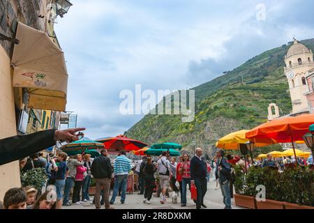 Vernazza Italia - Aprile 24 2011; turisti in Piazza Marconi sotto la torre dell'orologio della Chiesa di S. Margherita di Antiochia e colline circostanti. Foto Stock