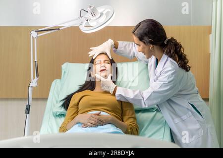 Medico o dermatologo che esamina la pelle del viso di un giovane paziente prepararsi prima di un intervento di lifting. Atmosfera presso il reparto di chirurgia estetica in h Foto Stock