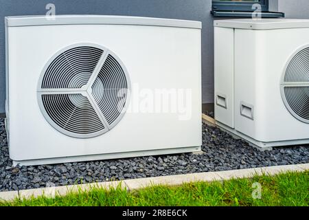 Due pompe di calore con fonte d'aria installate all'esterno di una nuova e moderna casa cittadina, concetto di energia rinnovabile verde della pompa di calore Foto Stock