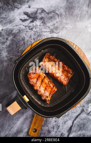 Cucina moderna - preparare succose costolette con salsa di miele in airfryer, carne alla griglia Foto Stock