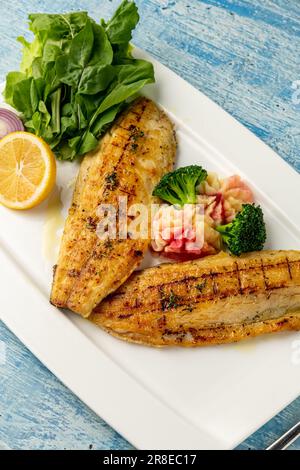 Filetto di branzino alla griglia servito con garnishes in un raffinato ristorante Foto Stock