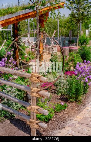 Particolare della recinzione naturale del giardino fatta di pali e corde di legno con piante autoctone e patio Foto Stock