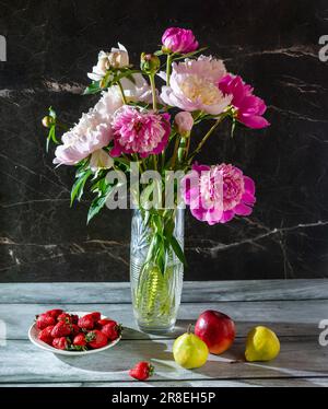 Una bella vita morta con peonie in vaso e frutta su fondo di marmo scuro Foto Stock