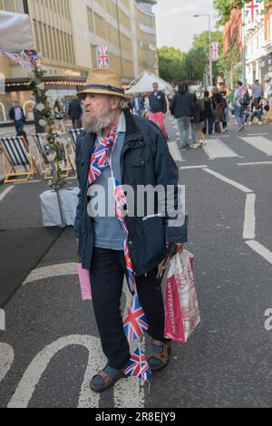 Il Kings Road, Platinum Jubilee Street Party, che sostiene l'appello britannico alla crisi della Croce Rossa Ucraina. La Kings Road è in parte chiusa al traffico. Un uomo più anziano, un residente con un mucchio intorno al collo, vagava per la strada, un po' peggio per l'usura - ubriaco. Chelsea, Londra, Inghilterra 4 giugno 2022. 2020 UK HOMER SYKES Foto Stock