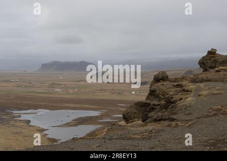 Paese sulla costa dell'oceano Atlantico. Piccolo lago circondato da montagne coperte di muschio e lichene in autunno. Cielo nuvoloso. Dyrholaey, sout Foto Stock