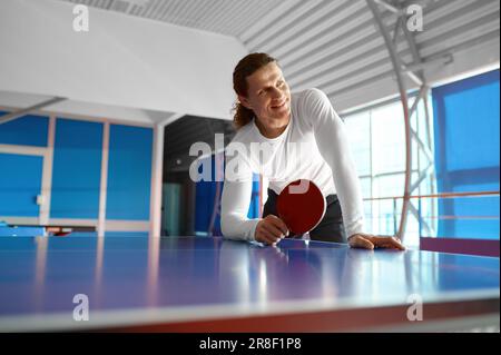 Sportivo soddisfatto che si riposa dopo l'allenamento seduto sul tavolo da tennis Foto Stock