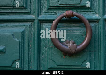 Vecchio battente porta ad anello in bronzo su un portale in legno dipinto di verde Foto Stock