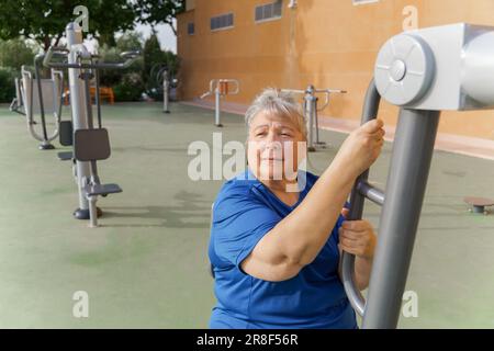 donna obesa attiva anziana in abbigliamento sportivo allenarsi su una palestra in una palestra del parco mentre si ascolta la musica con le cuffie Foto Stock