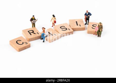 Crisi - lettere in legno Scrabble disposti a incantare 'crisi' circondato da piccole figurine raffiguranti vari gruppi di età. Foto Stock