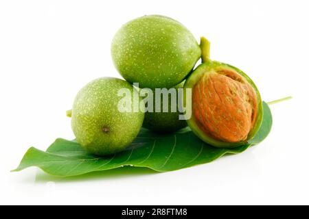 Mature rotto noci con foglie verdi isolati su sfondo bianco Foto Stock