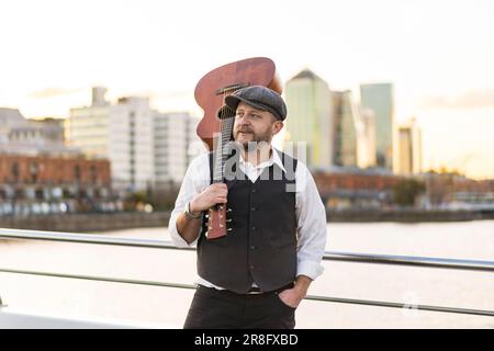 Ritratto di un musicista che guarda lontano mentre tiene la chitarra sulla spalla Foto Stock