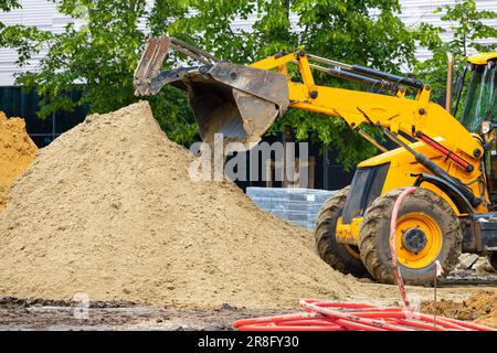 l'escavatore giallo produce lavori di terra sulla strada. l'escavatore giallo scava il terreno Foto Stock