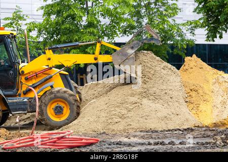 l'escavatore giallo produce lavori di terra sulla strada. l'escavatore giallo scava il terreno. Foto di alta qualità Foto Stock