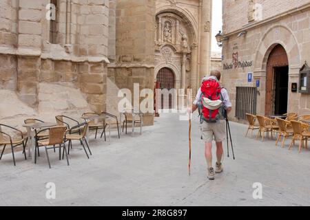 Via con edifici in pietra arenaria e un pellegrino, Viana, Navarra regione, Paesi Baschi, Spagna Foto Stock