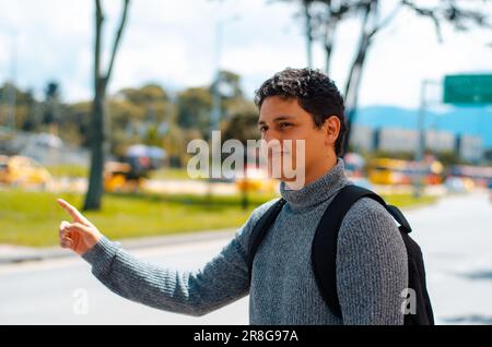 Uomo che aspetta l'autobus alla fermata dell'autobus in strada Foto Stock