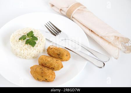 Gnocchi di merluzzo, o 'bolinhos de bacalhau', molto famosi nella gastronomia portoghese. Piatto di pasticcini di merluzzo servito con riso bianco. Foto Stock