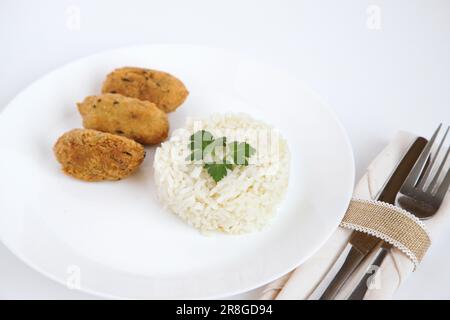 Gnocchi di merluzzo, o 'bolinhos de bacalhau', molto famosi nella gastronomia portoghese. Piatto di pasticcini di merluzzo servito con riso bianco. Foto Stock