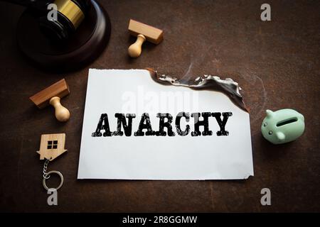 Anarchia. Un foglio di carta bianco che brucia su uno sfondo di metallo arrugginita. Foto Stock