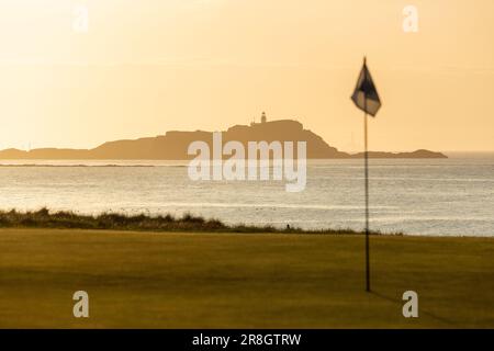 Un bel tramonto sull'isola di Fidra con una bandiera da golf sul campo da golf North Berwick in primo piano, North Berwick, Scozia Foto Stock