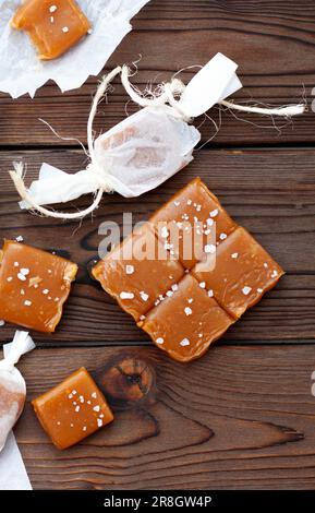 Caramelle al caramello salato con scaglie di sale marino su sfondo rustico in legno Foto Stock