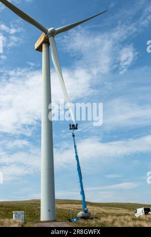 Ingegneri che utilizzano una piattaforma di lavoro mobile elevabile (raccoglitrice di ciliegie) per lavorare sulla pala di una turbina eolica a Steele's Knowe, Perth e Kinross, Scozia Foto Stock