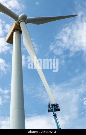 Ingegneri che utilizzano una piattaforma di lavoro mobile elevabile (raccoglitrice di ciliegie) per lavorare sulla pala di una turbina eolica a Steele's Knowe, Perth e Kinross, Scozia Foto Stock