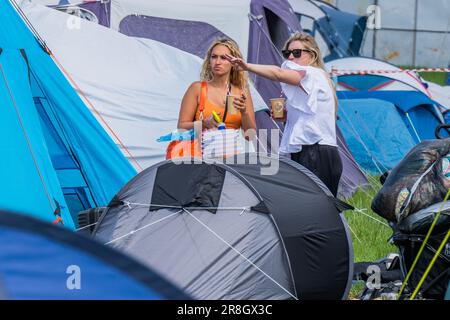 Glastonbury, Regno Unito. 21st giugno, 2023. La gente arriva il primo giorno. Quelli già sistemati in viaggio leggero e sono in buoni spiriti, nuovi arrivi faticosi nel fango leggero e sotto sacchi pesanti - il 2023 Festival di Glastonbury, Worthy Farm, Glastonbury. Credit: Guy Bell/Alamy Live News Foto Stock