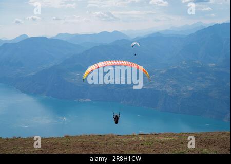 I parapendio salta dalla cima del Monte Baldo, verso Maclesine e il Lago di Garda in Italia Foto Stock