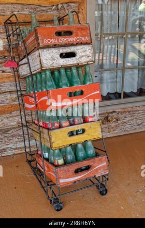 Varie bottiglie vuote Coca-Cola in casse di soda di legno vintage impilate verticalmente in un supporto di filo contro un edificio all'aperto vista primo piano Foto Stock