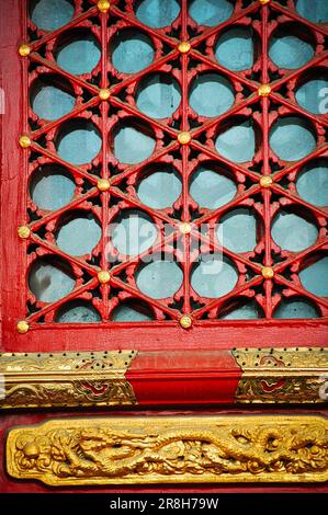 Una porta in legno intagliato in una profonda tonalità rossa con intricati dettagli in vetro e ottone Foto Stock