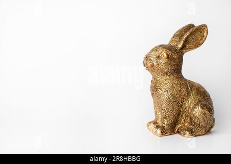 Figurina di coniglio d'oro su sfondo bianco. Spazio libero Foto Stock