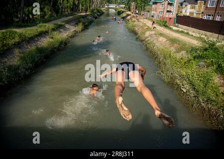 Pulwama, India. 21st giugno, 2023. Un ragazzo salta in un canale durante una calda giornata a Pulwama. La temperatura massima in Srinagar è aumentata a 34,0°C ed è stata di 4,8°C al di sopra della norma per la stagione. La temperatura di oggi ha superato il precedente più alto di 33,3°C registrato solo ieri, ha detto l'ufficiale. (Foto di Idrees Abbas/SOPA Images/Sipa USA) Credit: Sipa USA/Alamy Live News Foto Stock