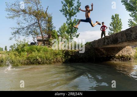 Pulwama, India. 21st giugno, 2023. Un ragazzo salta in un canale durante una calda giornata a Pulwama. La temperatura massima in Srinagar è aumentata a 34,0°C ed è stata di 4,8°C al di sopra della norma per la stagione. La temperatura di oggi ha superato il precedente più alto di 33,3°C registrato solo ieri, ha detto l'ufficiale. (Foto di Idrees Abbas/SOPA Images/Sipa USA) Credit: Sipa USA/Alamy Live News Foto Stock