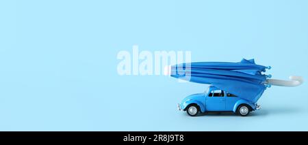 Auto giocattolo e mini ombrello su sfondo azzurro con spazio per il testo Foto Stock