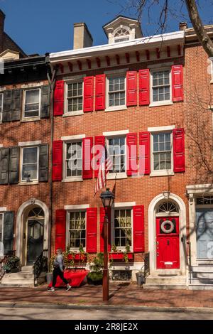 Casa coloniale in mattoni con porta rossa e persiane a Philadelphia, Pennsylvania Foto Stock