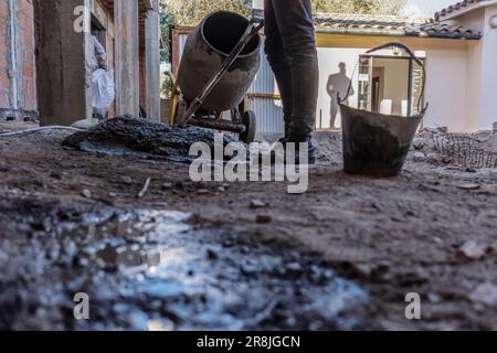 Lavoratore di costruzione prepara cemento ad un cantiere di costruzione. Primo piano di una persona non riconoscibile al piano terra. Foto Stock