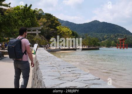 Il turista europeo che visita Itsukushima Jinja Otorii o la porta di Grand Torii sul mare di Miyajima, Hiroshima, Giappone. Foto Stock