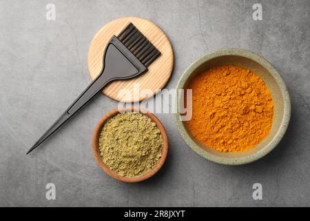 Composizione a posa piatta con henné e polvere di curcuma su tavolo grigio chiaro. Colorazione naturale dei capelli Foto Stock