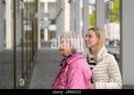 Vista laterale di una madre e di una figlia in piedi e guardando in una finestra dello shopping Foto Stock